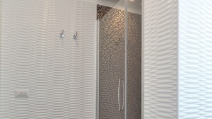Een moderne badkamer met een douchegedeelte, een bedieningspaneel en een structuurwand.