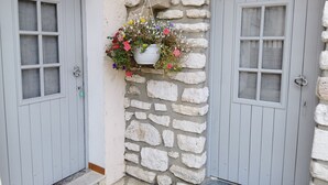 Un bâtiment doté de deux portes en bois grises et d’un mur en pierre.