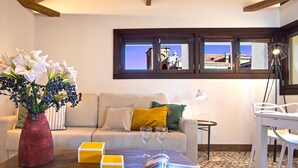 A living room with a sofa, a coffee table with a magazine, a vase with flowers, and a window with a view of a building. - Genteel Home Zacatin Penthouse 401 (Granada)
