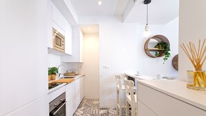 Una cocina moderna con armarios blancos, piso de baldosas estampadas y una lámpara colgante.