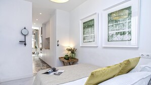 Ein modernes Schlafzimmer mit einem Bett, einem Nachttisch mit einer Vase und zwei gerahmten Kunstwerken an der Wand.