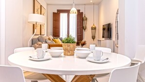 A dining area with a round table, white chairs, and a central woven basket with a plant. - Genteel Home Zacatin 203 (Granada)