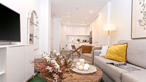 A modern living room with a grey sofa, a wooden coffee table, and a TV on a white cabinet. - Genteel Home Zacatin 203 (Granada)
