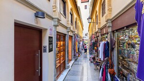 A narrow street with shops on either side, including a jewelry store and a clothing store. - Genteel Home Zacatin 103 (Granada)