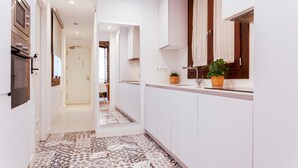 A modern kitchen with white cabinets, a patterned tile floor, and a potted plant on the counter.