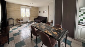 Un espai vital compacte amb taula de menjador, cadires, sofà i zona de cuina.