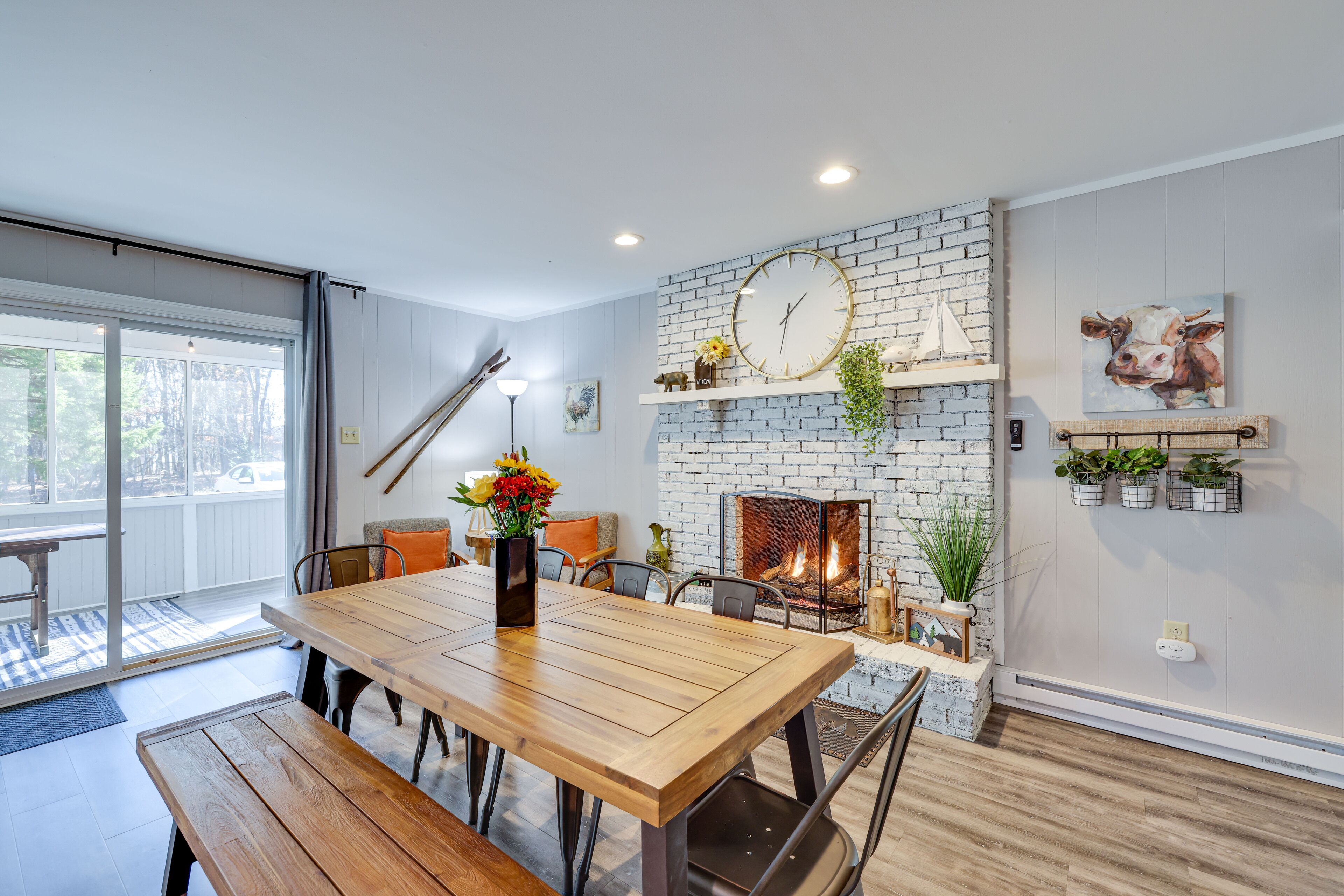 Un comedor moderno con chimenea de ladrillo, mesa de madera y bancos.