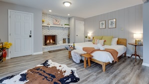 A bedroom with a fireplace, a bed with pillows, a bedside table, and a rug.