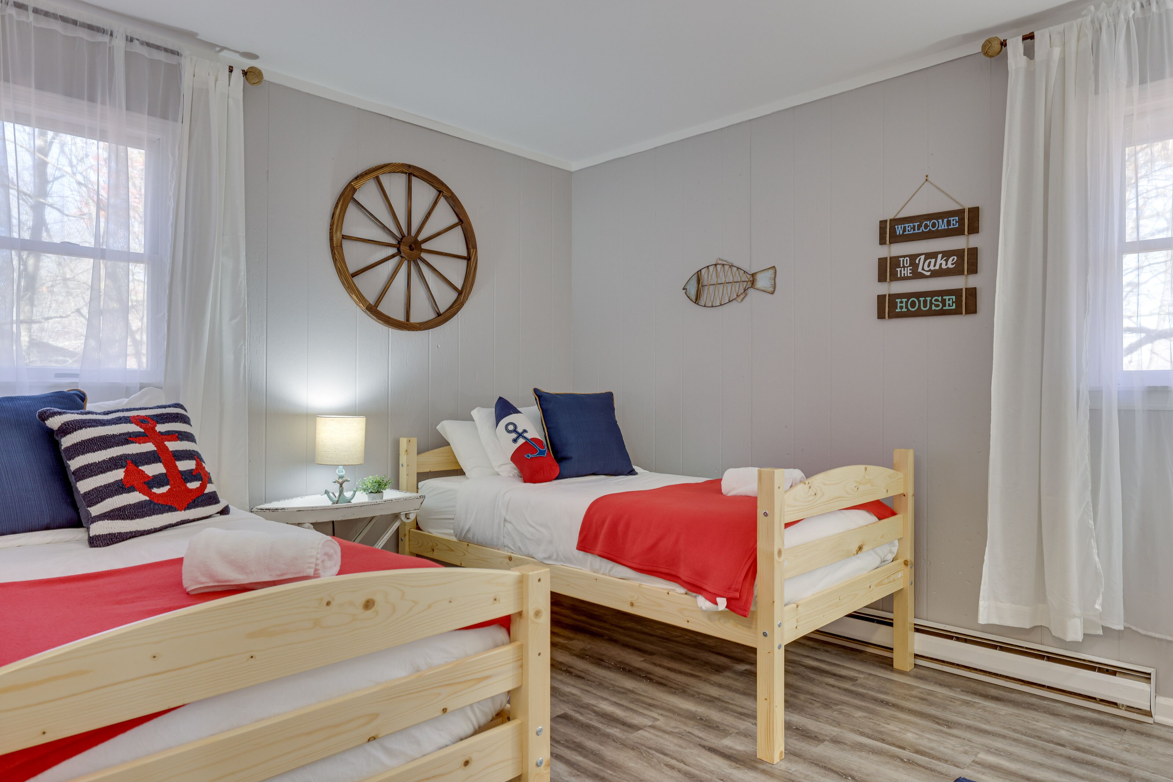 A bedroom with two wooden bunk beds, a round wall decoration, and a welcome sign.