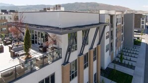 A multi-story building with a rooftop terrace, large windows, and a flat roof design. - Family Friendly Beach Theme with Hot Tub! (Draper)