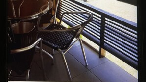 Un balcon donnant sur une rue, une chaise et une table.