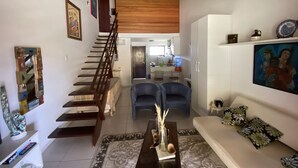Un vaste espace de vie comprenant un escalier menant à un deuxième étage, un coin repas et une cuisine située à l’arrière.