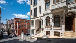 A street view of a building with a staircase leading to a door with a wooden frame. - Taksim suite (Istanbul)