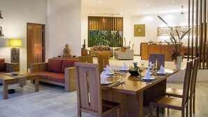A spacious living area with a wooden dining table set for a meal, a sofa, and a coffee table.