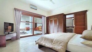 A spacious bedroom with a large bed, a television, and a sliding glass door leading to a balcony.