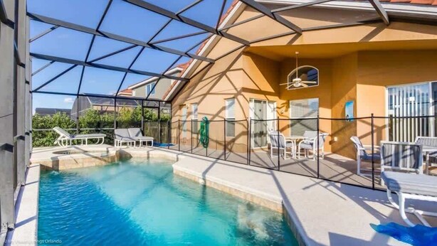 A swimming pool with a glass ceiling, surrounded by lounge chairs and tables, and a view of the surrounding area.