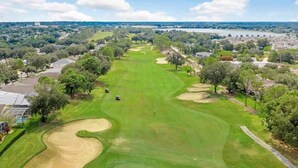Campo de golf con un camino despejado, búnkeres de arena y árboles.