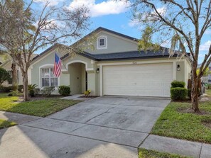 A single-story house with a garage, a front yard, and an American flag.