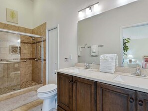 A bathroom with a shower, toilet, and vanity with a mirror.