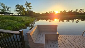 Une terrasse en bois avec un banc donnant sur une étendue d’eau calme, avec des arbres en arrière-plan.