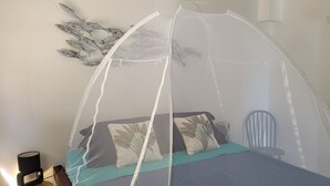 A bed with a canopy, a chair, and a wall-mounted decorative piece. - NEW - 5mn from the 1st beaches, Caribbean sea view, quiet and central, wifi (Sainte-Luce)