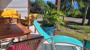 An outdoor patio with wooden furniture, a table, and a blue chair. - NEW - 5mn from the 1st beaches, Caribbean sea view, quiet and central, wifi (Sainte-Luce)