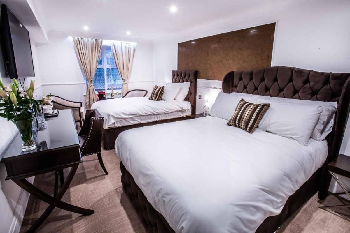A hotel room with two beds, a desk, and a TV.