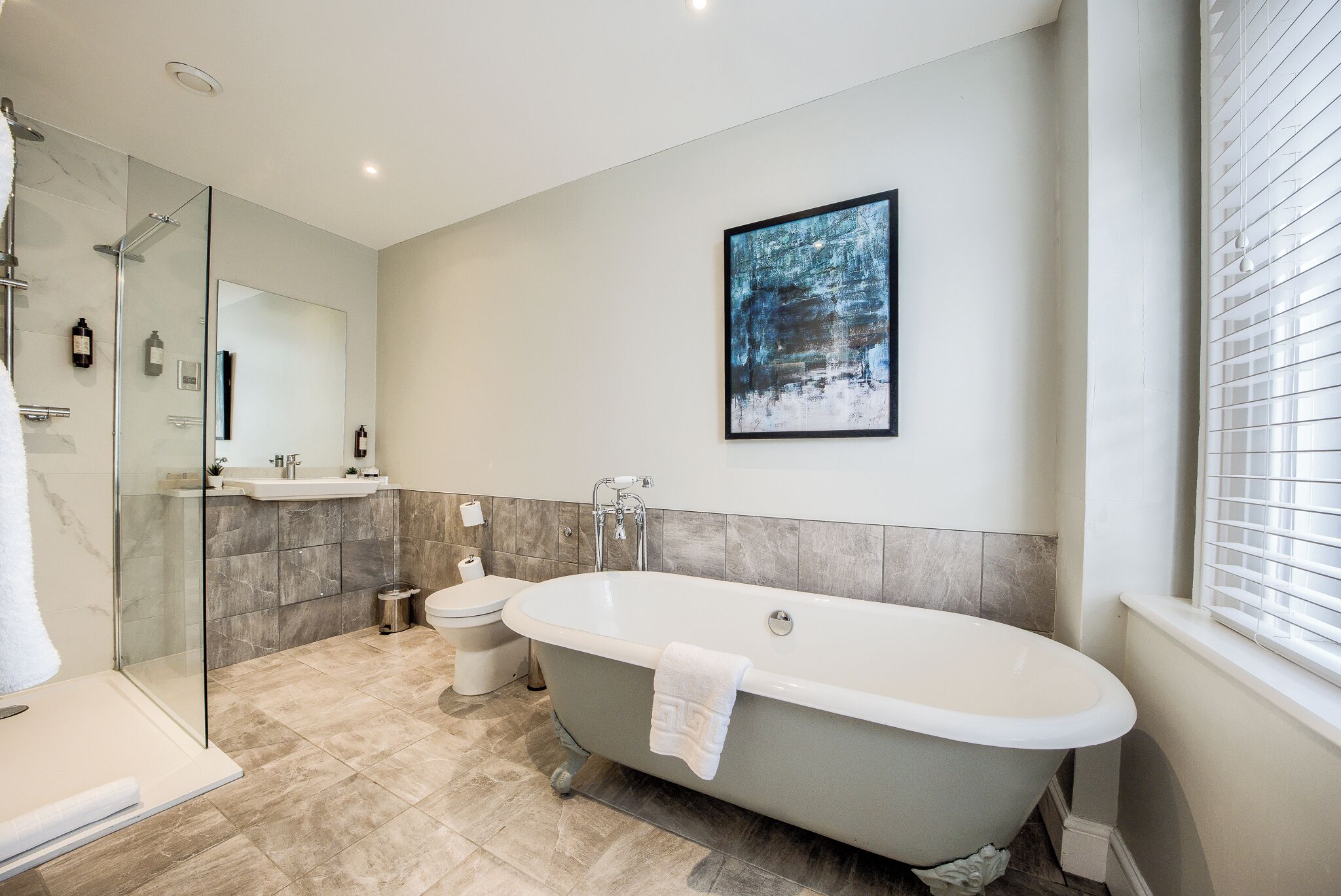 A modern bathroom with a freestanding bathtub, a glass-enclosed shower, a toilet, and a sink.