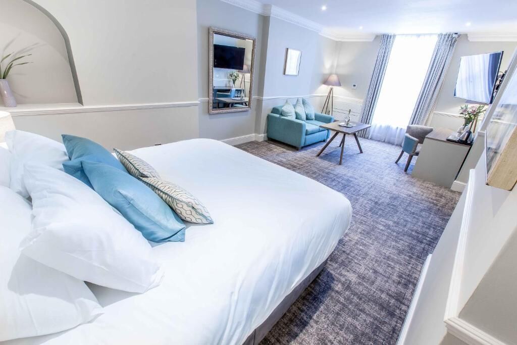 Habitación de hotel con una cama grande, un sofá, un escritorio y un televisor.