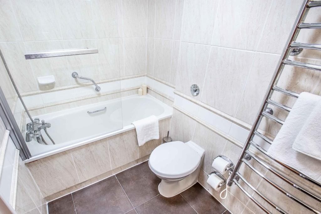 A bathroom with a bathtub, toilet, and a towel rack.