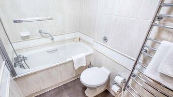 A bathroom with a bathtub, toilet, and a towel rack.