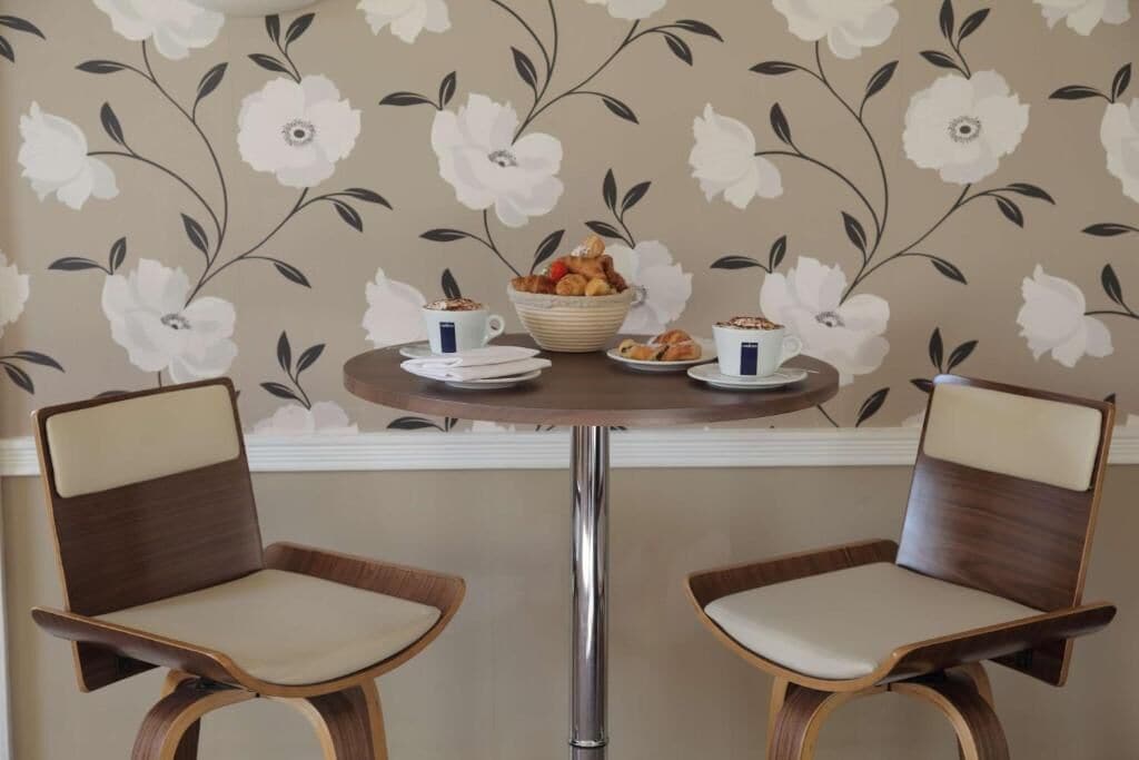 Ein Essbereich mit zwei Stühlen, einem Tisch und blumigem Wandpapier.