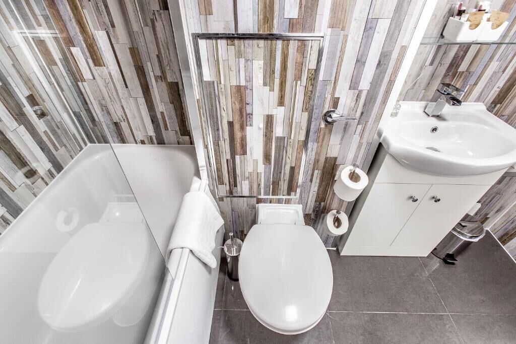 A modern bathroom with a white toilet, a bathtub, a sink, and a shower area.