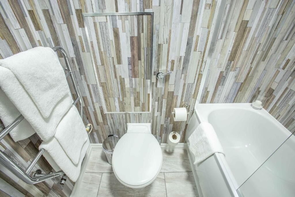 Une salle de bain au design moderne, comprenant des toilettes, une baignoire et un espace douche.