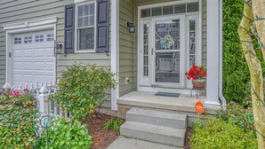 A house with a front porch, a garage, and a small garden with various plants and flowers.