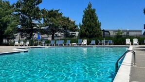 A clear blue pool with lounge chairs and a metal railing.