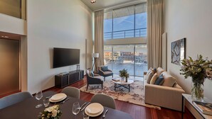 A modern living room with a dining area, large windows, and a view of the city. - Hyatt Regency Madrid Residences (Madrid)