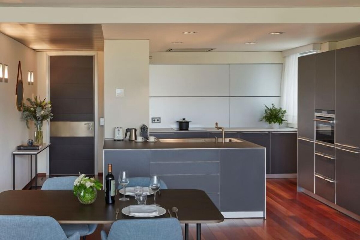 A modern kitchen with a central island, dark cabinetry, and a dining area with a table set for two.