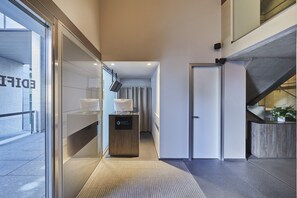 A modern hotel lobby with a reception desk, a glass wall, and a staircase. - Hyatt Regency Madrid Residences (Madrid)