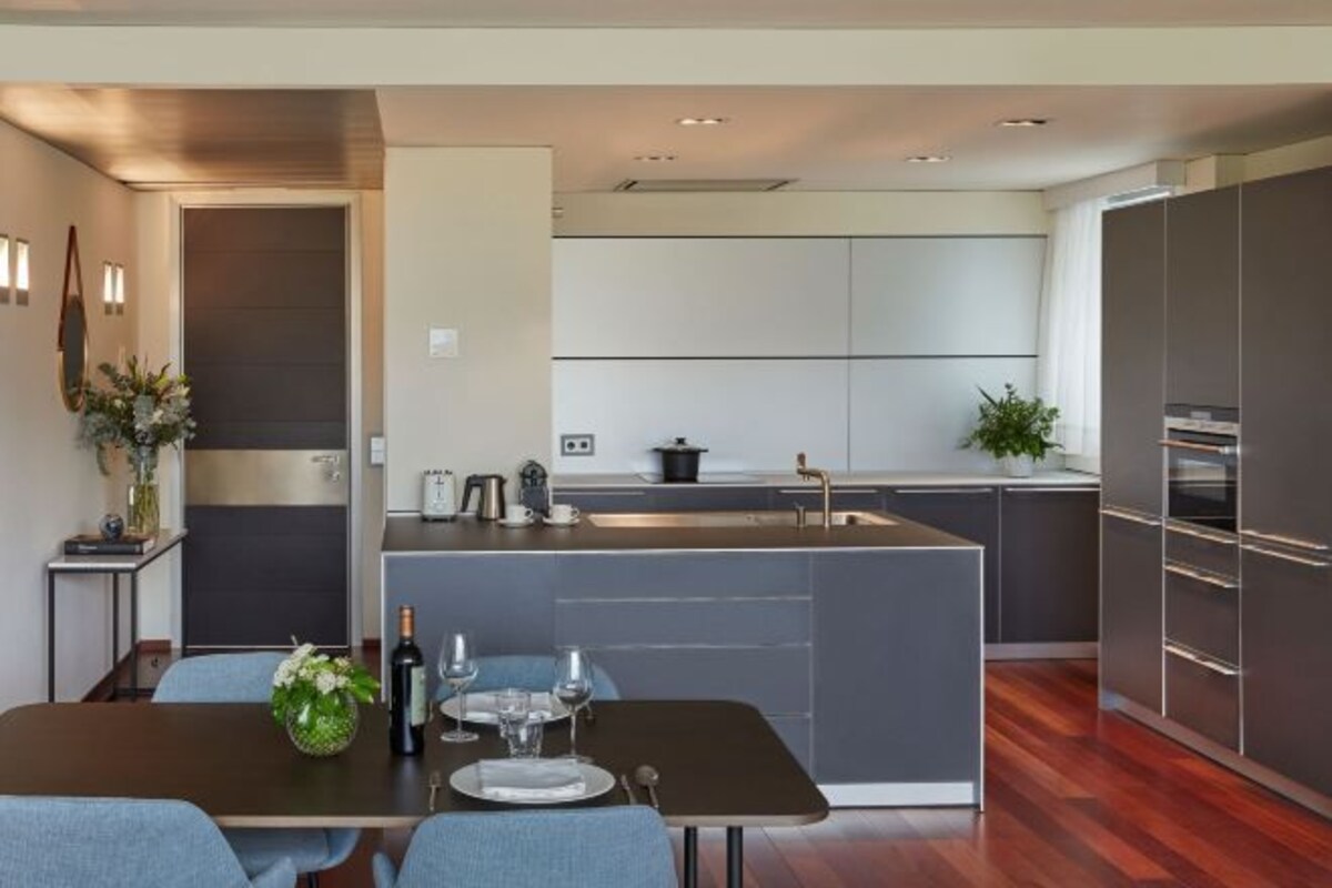 A modern kitchen with a central island, dark cabinetry, and stainless steel appliances.