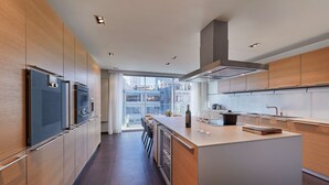 A modern kitchen with wooden cabinets, stainless steel appliances, and a large island. - Hyatt Regency Madrid Residences (Madrid)