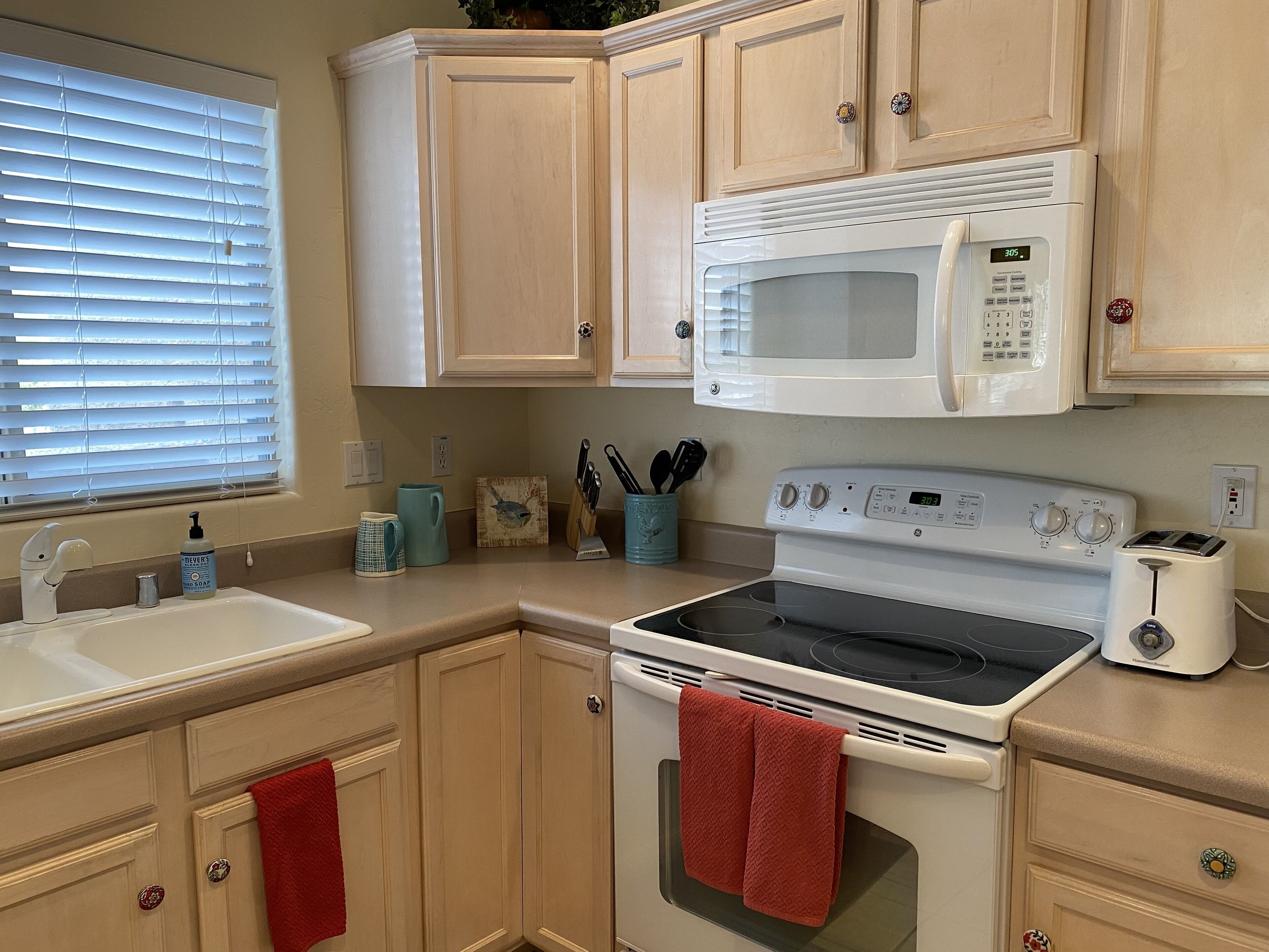 A kitchen with a white stove, oven, microwave, and a sink.