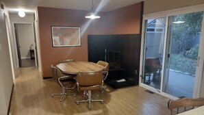 A dining area with a wooden table and chairs, a painting on the wall, and a sliding glass door leading to a patio. - Room with a View (Monticello)