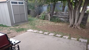 A concrete patio with a gas grill and a shed in the background. - Room with a View (Monticello)
