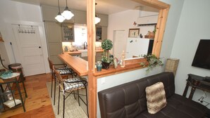 A living room with a brown leather sofa, a wooden coffee table, and a dining area with a wooden table and chairs. - ❤Riverfront Paradise - Butterfly Ranch on the River❤ (Dunsmuir)