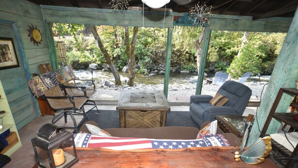 A rustic cabin with a wooden interior, a view of a stream, and outdoor seating. - ❤Riverfront Paradise - Butterfly Ranch on the River❤ (Dunsmuir)