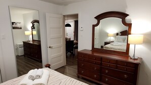 Ein Hotelzimmer mit Bett, einem Holzschrank, einem Spiegel und einer Lampe.