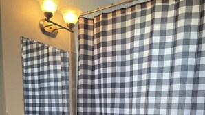 Un baño con cortina de ducha a cuadros, un lavabo con espejo y un inodoro.