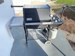 A portable Weber grill with a control panel, a fuel tank, and a grilling grate.