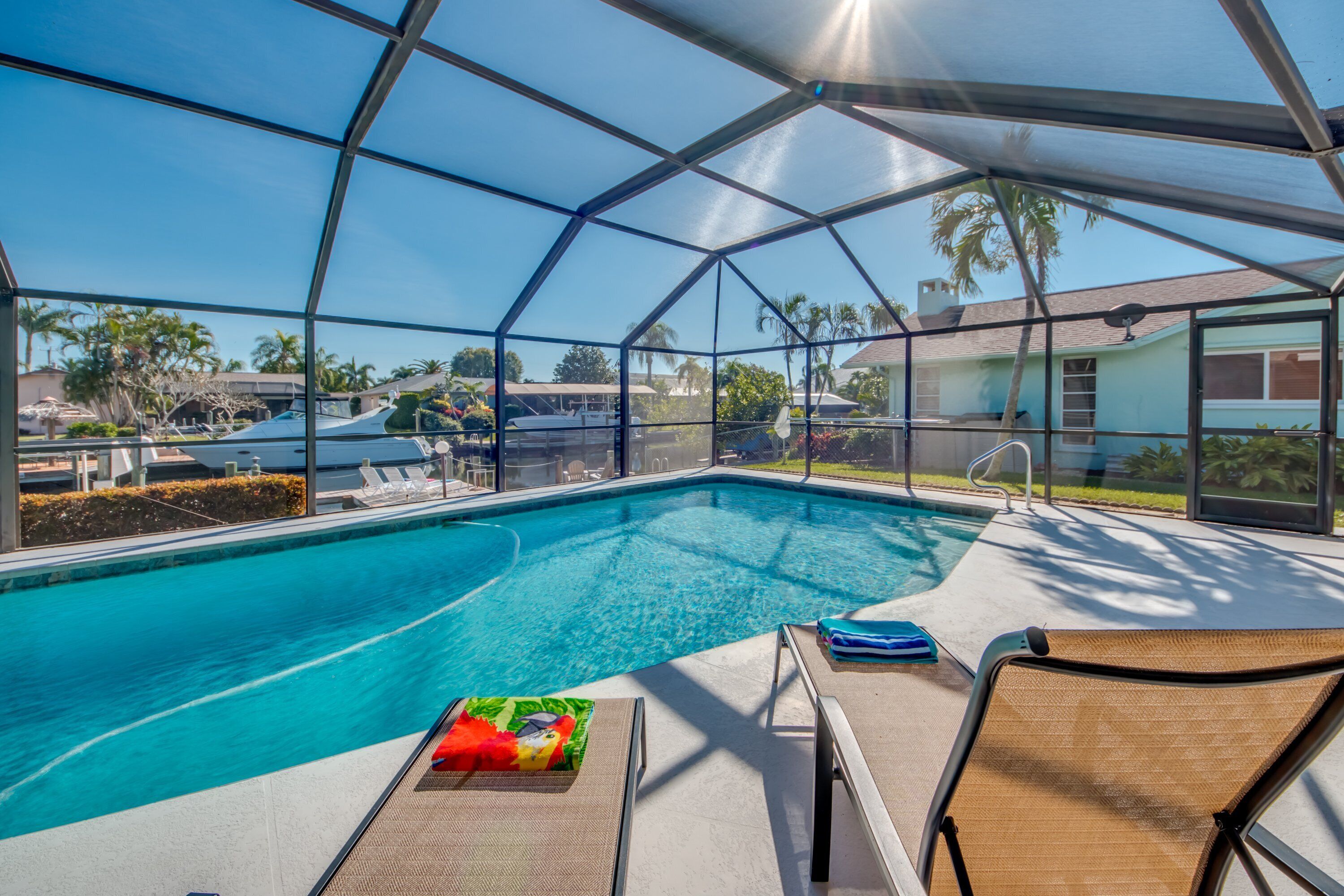 A covered swimming pool with lounge chairs and a poolside umbrella.